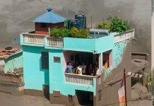 Family survives as powerful Nepal floodwaters destroy surrounding structures nearby.